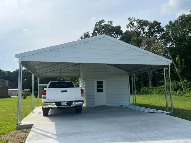 A pickup parked under a metal carport connected to an enclosed storage area